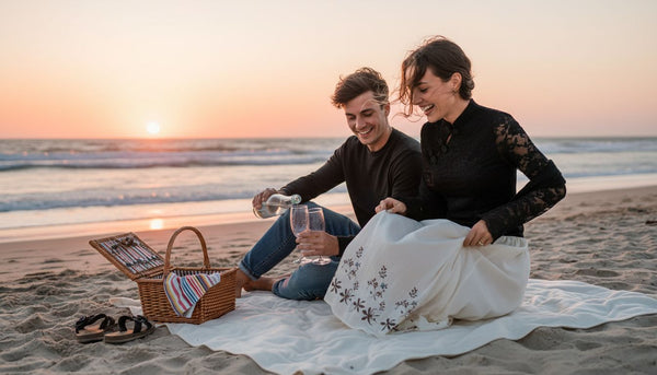 Couple enjoying picnic on beach at sunset